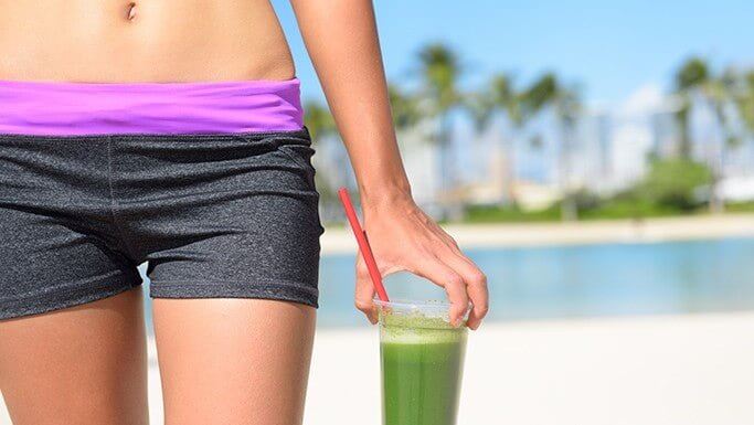 Healthy woman holding green juice, symbolizing how MD® Ultimate Green provides the benefits of drinking a daily superfood green juice