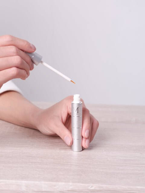 Wiping off excess MD Lash Factor serum to show only a small amount is needed for lash growth