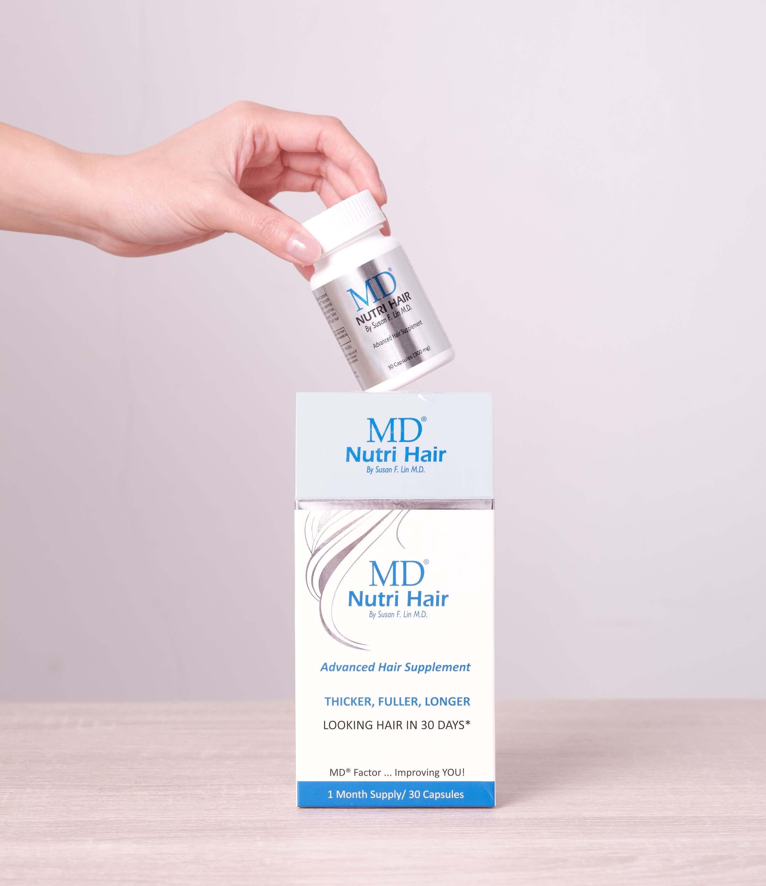 Hand removing MD Nutri Hair bottle from product box – premium hair growth supplement packaging from MD Hair with clean, drug-free formula