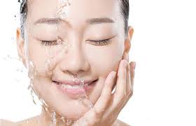 Young woman smiling with clear water splash on face – symbolizes refreshing hydration and glow from MD Ultimate Moisturizer

